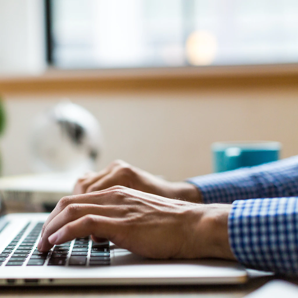 Close-up of hands typing on a laptop keyboard